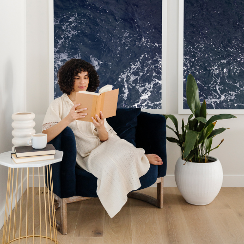 Woman doing her 5 minute daily morning routine reading a book while sitting in a blue chair